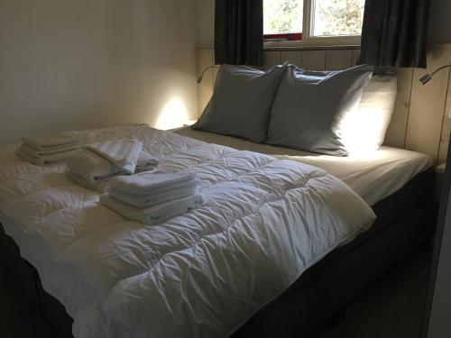 un letto bianco con cuscini e asciugamani bianchi sopra di Bungalows Dellewal a West-Terschelling
