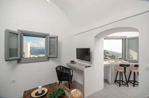 a living room with a table and chairs and windows at Nissos House Santorini in Akrotiri