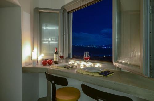 a table with wine glasses and a window with a view at Nissos House Santorini in Akrotiri