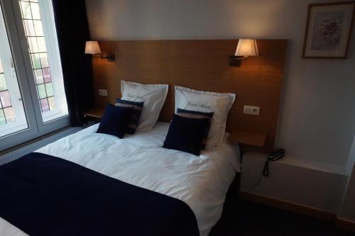a bedroom with a bed with white sheets and blue pillows at Hotel Asiris in Bruges