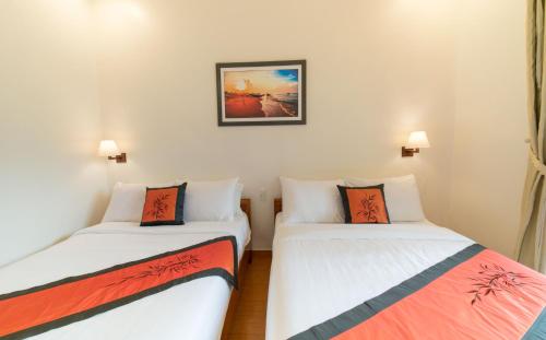 two beds in a room with white walls at Lakeview Villa Homestay in Hoi An