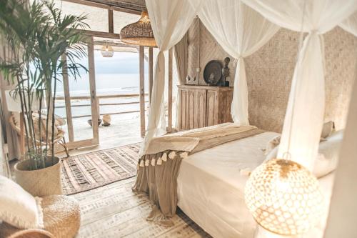 Schlafzimmer mit einem Himmelbett und Meerblick in der Unterkunft Dreamsea Bali in Uluwatu
