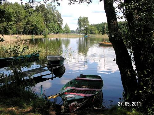 a boat sitting in the water next to a dock at domek nad jeziorem in Kujan