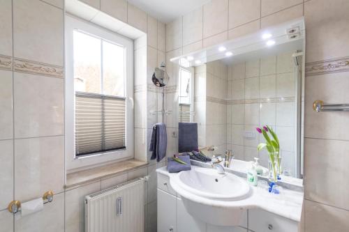 ein weißes Badezimmer mit einem Waschbecken und einem Spiegel in der Unterkunft Villa Mona Lisa Whg. 6 in Göhren