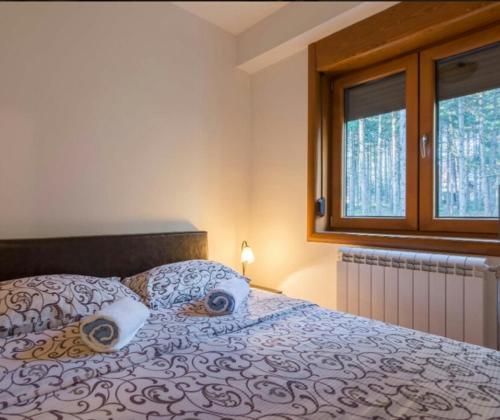 1 dormitorio con 1 cama con 2 almohadas y ventana en Apartment Kiki, en Zlatibor
