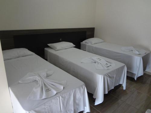 a room with two beds with white linens on them at Golden Hotel in Vilhena