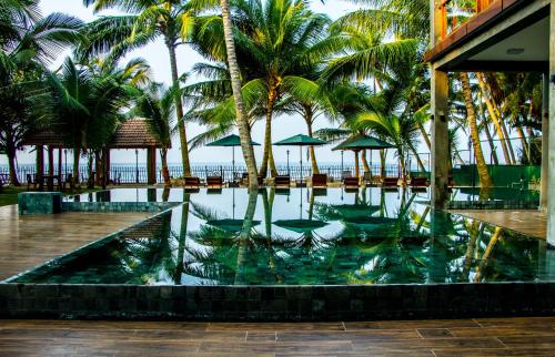 uma piscina com palmeiras e uma praia em Hikka Sandy Pearl Beach Resort em Hikkaduwa