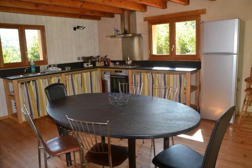 y cocina con mesa, sillas y nevera. en Les Ondines, en Gembrie