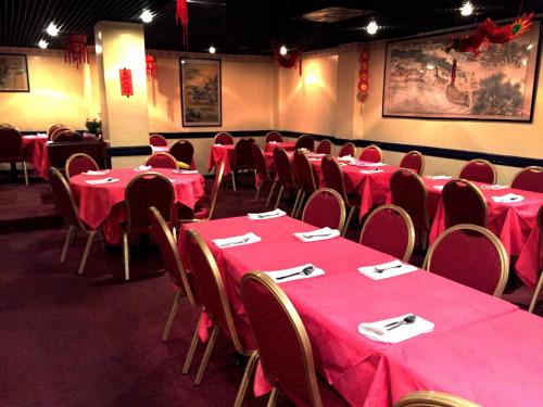 a room with tables and chairs with red table cloths at The Oasis Hotel in Harlow