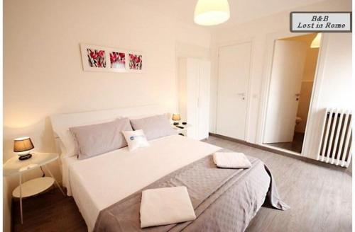 Un dormitorio con una gran cama blanca y un espejo. en B&B Lost in Rome, en Roma