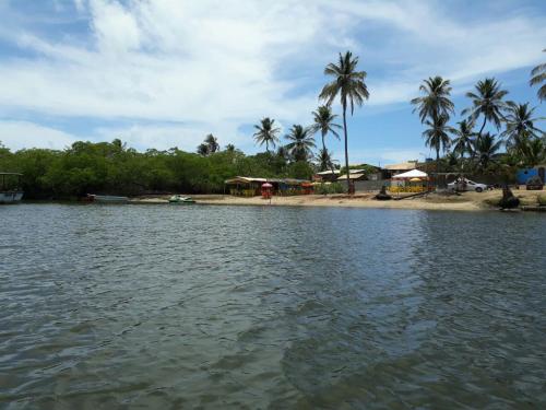 a body of water with a beach and palm trees at Pousada Club de Poças in Conde