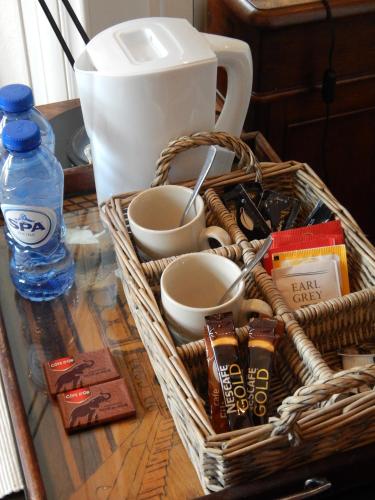 a basket on a table with cups and a bottle of water at Les Remparts in Binche