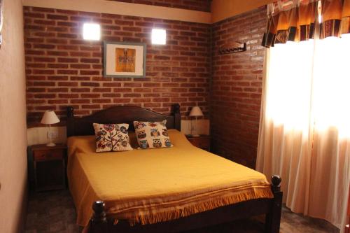 1 dormitorio con cama y pared de ladrillo en La Posada Del Poeta en Mina Clavero
