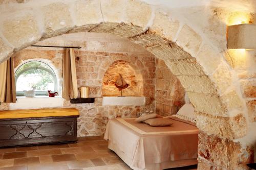 a bedroom with a bed and a stone wall at Masseria Camarda in Ceglie Messapica