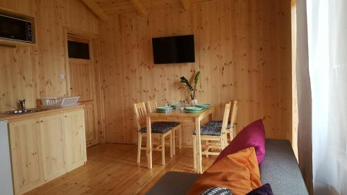 a dining room with a table and chairs and a television at Domy "Pod Brzozami" in Ustka