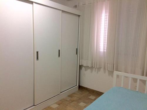 1 dormitorio con armarios blancos, 1 cama y ventana en Edifício Afonso Delambert, en Florianópolis