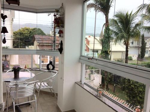 Habitación con 2 ventanas, mesa y sillas en Edifício Afonso Delambert, en Florianópolis