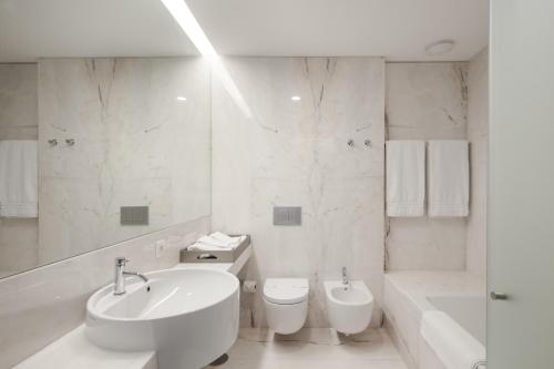 uma casa de banho branca com um lavatório, uma banheira e um WC. em Torre de Gomariz Wine & Spa Hotel em Cervães