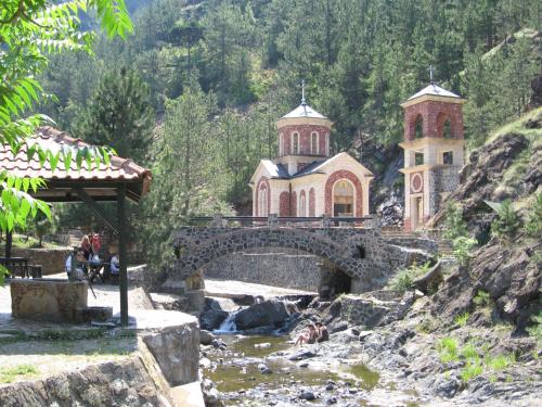 a bridge over a river with a church on a hill at Apartman Draga in Mokra Gora
