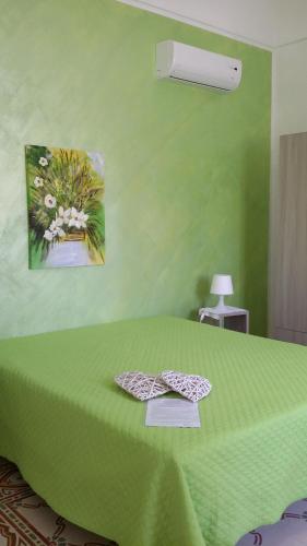 ein grünes Schlafzimmer mit einem grünen Bett mit zwei Bögen in der Unterkunft La Casa Dei Nonni in Custonaci