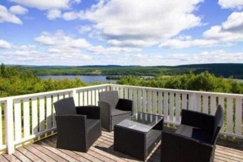a deck with chairs and a table and a view at Sunne Stugcenter 18 in Gräsmark