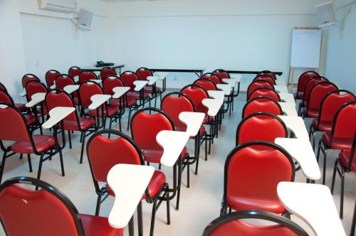 an empty room with red chairs and desks at Hotel Linhatur in Linhares