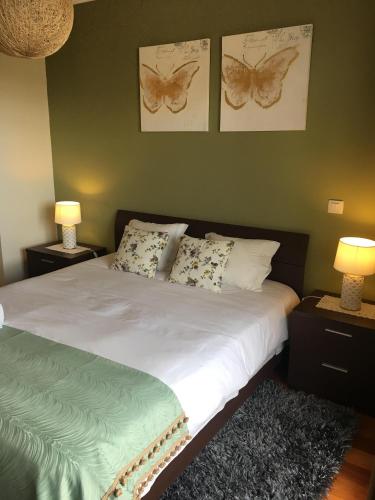 a bedroom with a bed with two lamps and butterflies on the wall at Atlantis Apartment in Câmara de Lobos