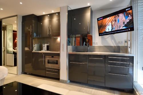 Il comprend une cuisine avec des placards en acier inoxydable et une télévision à écran plat. dans l'établissement Elixxir, au Cap d'Agde