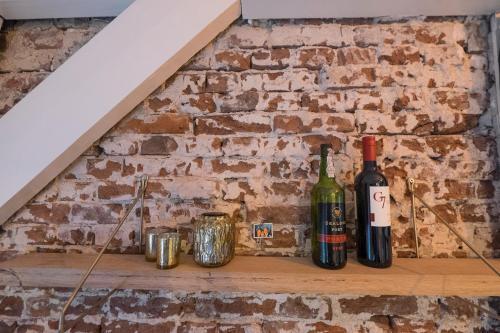 two bottles of wine sitting on a shelf against a brick wall at B&B Numero 14 in Amsterdam