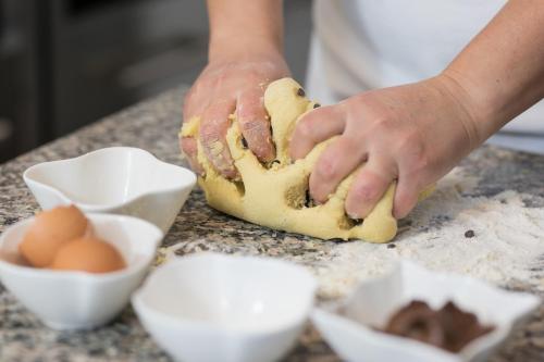 a person kneading dough on a table with eggs at R&B La Gerla Blu in Tolmezzo