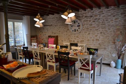 une salle à manger avec une table, des chaises et de la nourriture. dans l'établissement Chambres d'hôtes Villa de Vienne-en-Arthies, à Vienne-en-Arthies