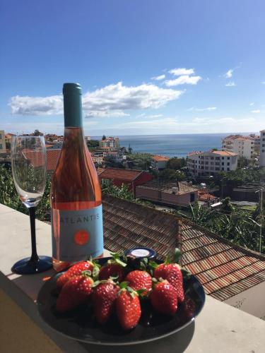 a plate of strawberries and a bottle of wine and a glass at Atlantis Apartment in Câmara de Lobos