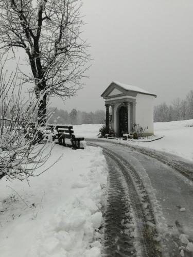 a bench and a building in the snow at R&B La Gerla Blu in Tolmezzo