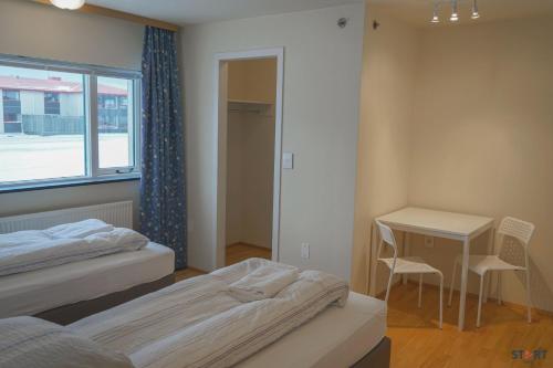 a bedroom with two beds and a desk and a window at Start Keflavík Airport in Keflavík
