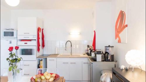 - une cuisine avec des placards blancs et un bol de fruits dans l'établissement Le Petit Zénith, à Saint-Herblain