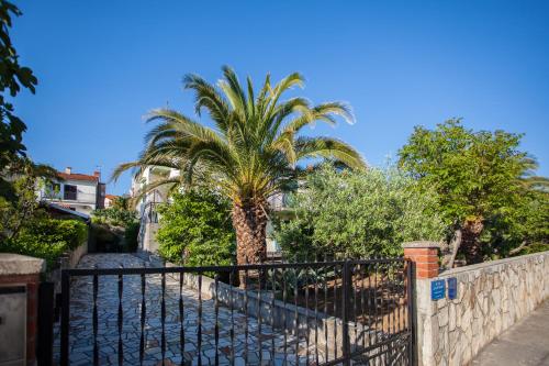 une clôture avec un palmier devant une maison dans l'établissement Villa Vosilla Apartments, à Cres