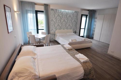 um quarto de hotel com duas camas e uma mesa e cadeiras em Eden Park em Marina di Montemarciano