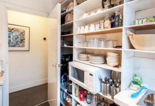 a kitchen with white shelves with dishes and a microwave at Great Loft & Location by Belsize Park tube in London