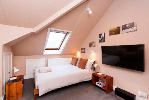 a bedroom with a bed and a large tv at Great Loft & Location by Belsize Park tube in London