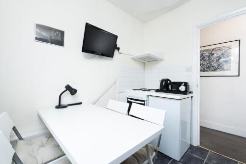 um quarto branco com uma cozinha com uma secretária e uma televisão em Great Loft & Location by Belsize Park tube em Londres
