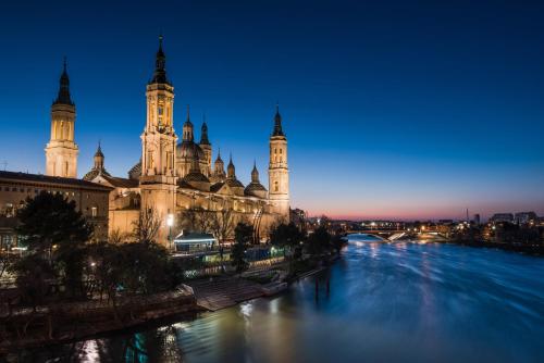 a view of a building and a river at night at Hotel Rio Arga in Zaragoza