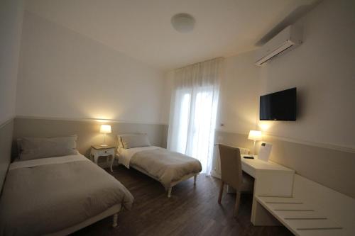 a hotel room with two beds and a desk and a television at Principe in Bari