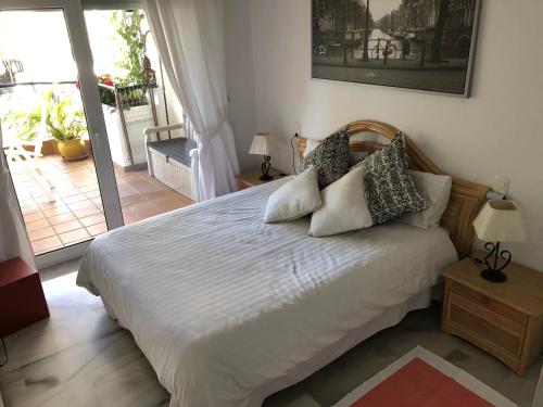 a bedroom with a bed with pillows and a balcony at Mi Capricho in Sitio de Calahonda
