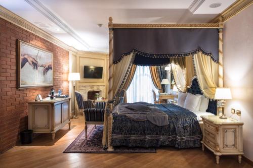 a bedroom with a canopy bed and a desk at Xheko Imperial Luxury Hotel & SPA in Tirana