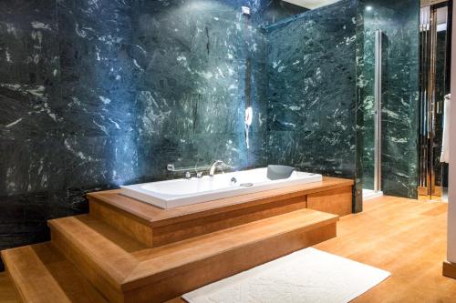 a bathroom with a bath tub with a black wall at Xheko Imperial Luxury Hotel & SPA in Tirana