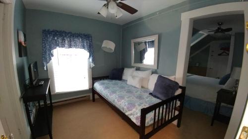 a small bedroom with a bed and a mirror at Benjamin Prescott Inn in Jaffrey