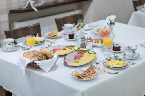 a white table topped with plates of food and glasses of orange juice at Hotel Awo in Gniezno
