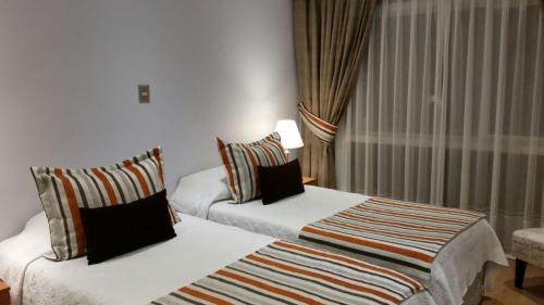 a hotel room with two beds and a window at Hotel Puerta del Lago in Puerto Varas