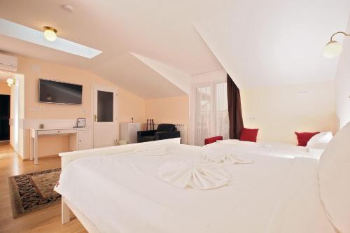 a white bedroom with two white beds and a tv at Boutique Apartments Oradea in Oradea