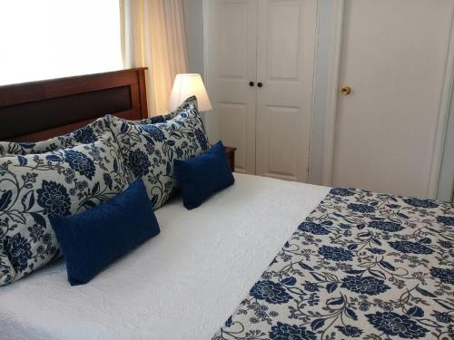 a bedroom with a bed with blue and white pillows at Hotel Puerta del Lago in Puerto Varas